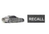 A miniature gray sports car next to a black sign that reads 'RECALL'