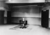 An empty execution room featuring an electric chair on a rug