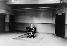 An empty execution room featuring an electric chair on a rug
