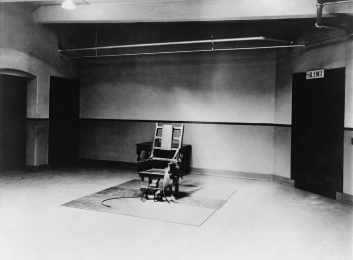 An empty execution room featuring an electric chair on a rug