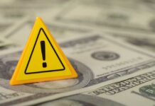 Daily War Operations Cost STUNS Taxpayers A yellow warning sign placed on a pile of dollar bills