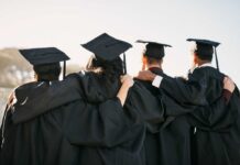 Group of graduates standing together with arms around each other, wearing caps and gowns