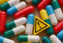 Colorful capsules scattered around a yellow warning sign