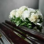 A floral arrangement of white roses and greenery on a polished casket