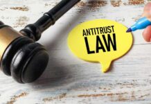A gavel next to a yellow speech bubble note that reads 'ANTITRUST LAW'