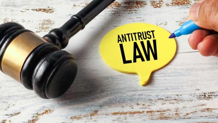 A gavel next to a yellow speech bubble note that reads 'ANTITRUST LAW'
