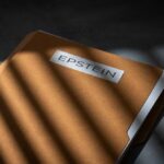 BOMBSHELL Files Link Top Trump Official to Epstein A brown folder with the name 'EPSTEIN' on it, partially illuminated by light and casting shadows