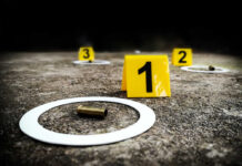 Crime scene with evidence markers and a bullet casing on the ground