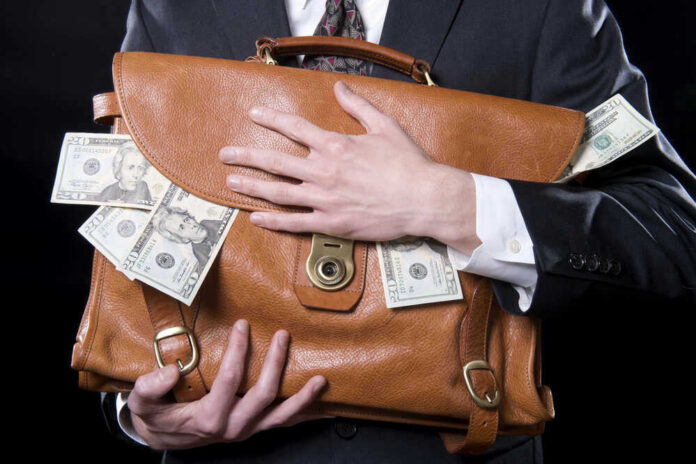 shutterstock_133129220-1-1 Person clutching leather bag with money sticking out.