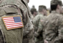Greene’s U.S. Troops Warning: Revolution Looms? U.S. soldiers in camouflage uniforms with American flag patch.