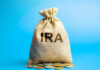 A burlap bag labeled 'IRA' with coins scattered around it