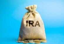 A burlap bag labeled 'IRA' with coins scattered around it