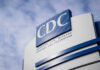CDC Downplays Lethal Cruise Outbreak CDC building sign against a cloudy sky.