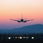 2 A.M. Shutdown Stuns Airline Flyers An airplane approaching for landing against a colorful sunset sky