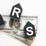 IRS SCANDAL: Millions Denied Refunds? Blocks spelling 'IRS' placed on top of hundred dollar bills featuring Benjamin Franklin