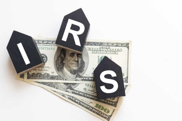shutterstock_2510814485.jpg Blocks spelling 'IRS' placed on top of hundred dollar bills featuring Benjamin Franklin