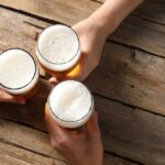 Three hands holding beer glasses in a toast