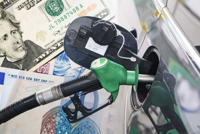 A fuel pump nozzle inserted into a car's gas tank with various currency notes in the background