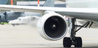 Close-up view of a jet engine and landing gear on an aircraft at an airport