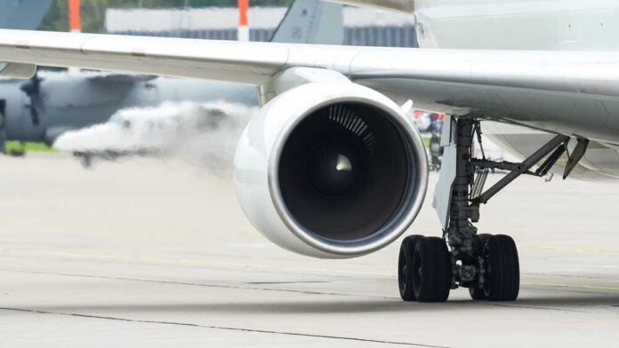 Close-up view of a jet engine and landing gear on an aircraft at an airport
