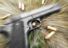 Shocking Courthouse Shooting Rocks Community! Pistol and bullets on grass with motion blur effect.