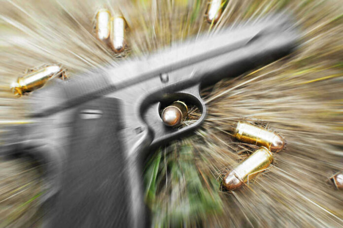 shutterstock_420570037 Pistol and bullets on grass with motion blur effect.