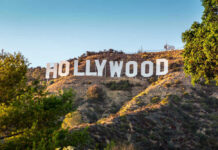 Celebrity Justice, Again: LaBeouf Skates Hollywood Sign on a green hillside, sunny day.