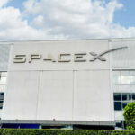 SpaceX IPO Made THIS Immigrant a Millionaire SpaceX building with logo and blue sky.