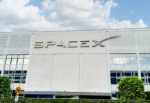 SpaceX IPO Made THIS Immigrant a Millionaire SpaceX building with logo and blue sky.