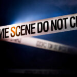 Police tape reading 'CRIME SCENE DO NOT CROSS' in a dark setting