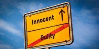 A yellow road sign displaying 'Innocent' pointing up and 'Guilty' crossed out