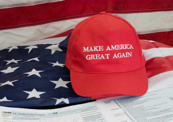 shutterstock_2240568885 Red Make America Great Again hat on American flag