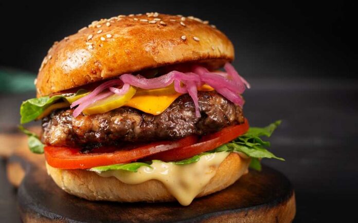 Beef,Hamburger.,Sandwich,With,Beef,Burger,,Tomatoes,,Cheese,,Pickled,Cucumber Close-up of a gourmet cheeseburger with lettuce, tomato, and pickled onions