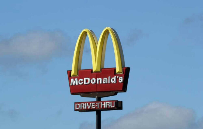 shutterstock_2433110395-1 McDonalds drive-thru sign against a blue sky.