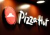 Illuminated Pizza Hut sign on a dark background