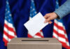 Governor’s Decision Sparks Election Fury Hand casting a vote into a ballot box.
