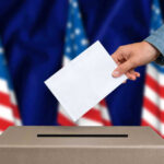 Governor’s Decision Sparks Election Fury Hand casting a vote into a ballot box.