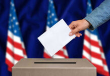 Hand casting a vote into a ballot box.