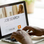Vanishing Workers, Falling Rate — What Broke? Person searching for jobs on a laptop.