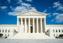 Supreme Court building with grand columns and steps under a blue sky