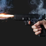 Teen Gunfight Shocks Seattle Festival A hand holding a gun with smoke and a flash from the muzzle