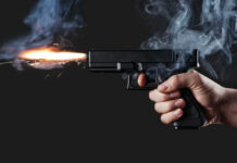 Teen Gunfight Shocks Seattle Festival A hand holding a gun with smoke and a flash from the muzzle