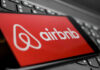 Airbnb’s AI Blacklists July 4 Travelers Airbnb logo on a phone screen, near keyboard.