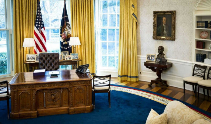 shutterstock_2442431237 Presidential office with desk, flags, and portraits.