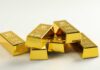 Buried Gold Rings Disrupt Historic Origin Story A stack of shiny gold bars arranged on a light background
