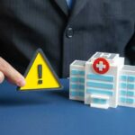 ER Surge Shocks Medical Professionals A business professional holding a warning sign next to a model of a hospital