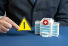 ER Surge Shocks Medical Professionals A business professional holding a warning sign next to a model of a hospital