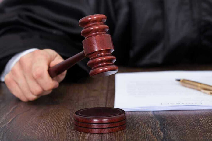 186812807 Judges hand holding gavel next to documents.