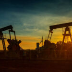 Gas Pain, Record Profits — Trump Explodes Oil pumpjacks silhouetted at sunset on a rural field