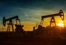 Oil pumpjacks silhouetted at sunset on a rural field